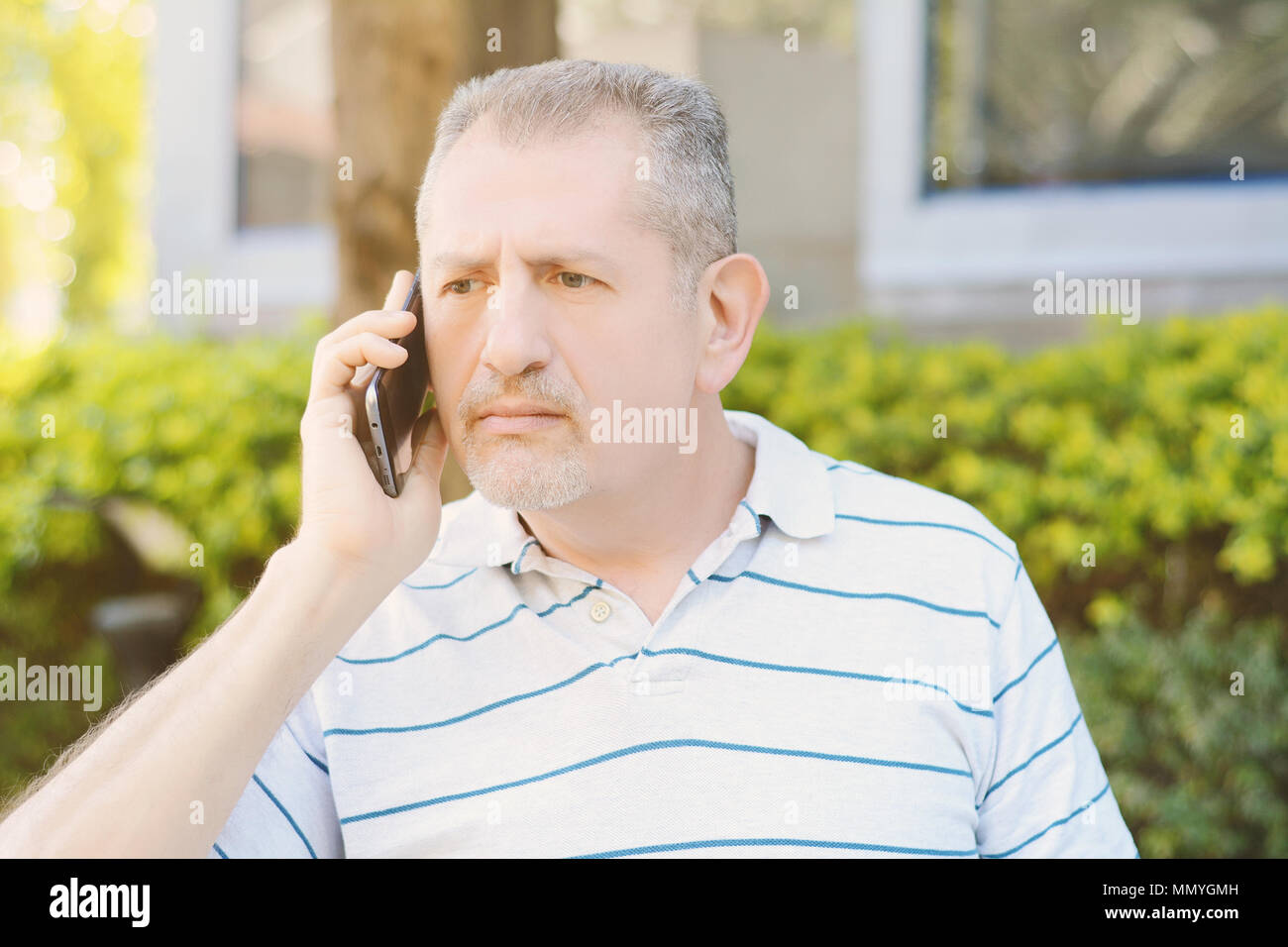 Besorgt, mittleres Alter Mann am Telefon zu sprechen in einem Park. Im Freien. Technologie Konzept. Stockfoto