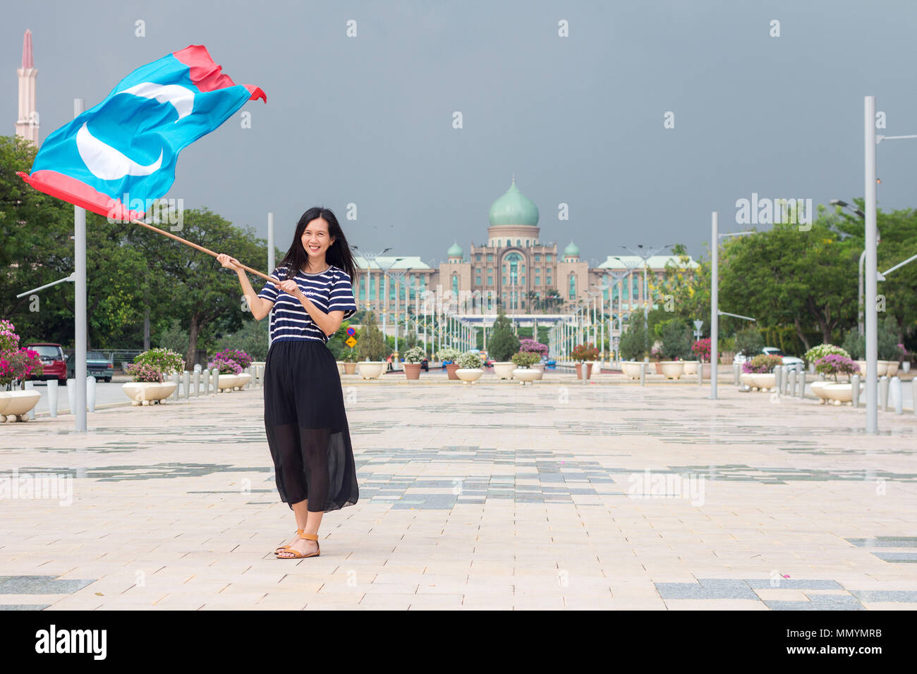 PUTRAJAYA MALAYSIA - 13. Mai 2018 - Eine weibliche PKR (Parti Keadilan) Anhänger fröhlich winkend die Flagge von Wining Partei vor der Regierung Anbieter-management Stockfoto