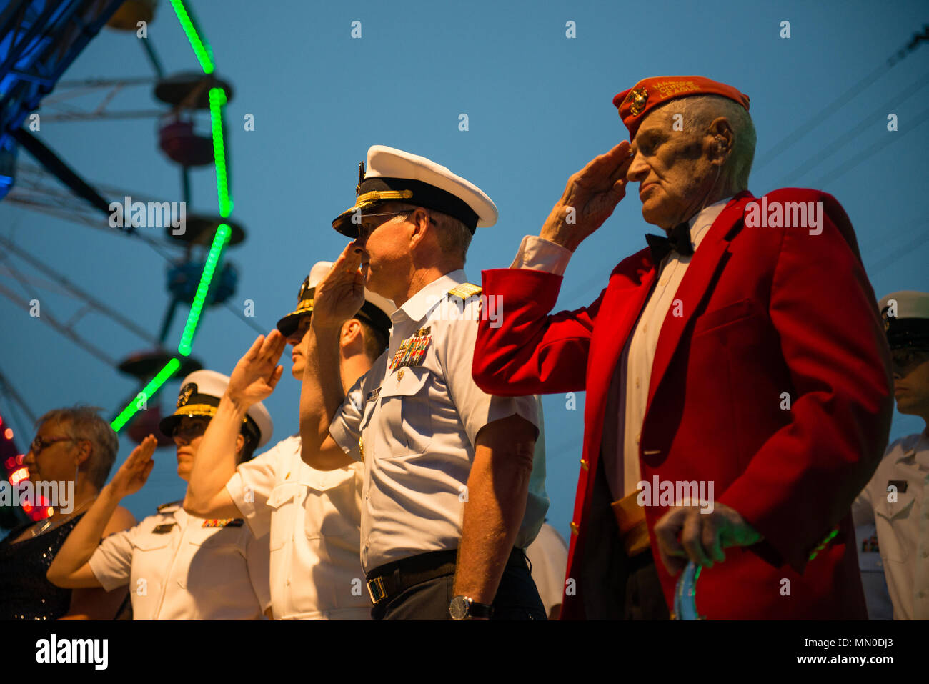 Coast Guard hinten Adm. Steven Poulin, Commander, First Coast Guard Bezirk (Mitte) und dem Zweiten Weltkrieg Marine Corps veteran Leroy Peasley (rechts) Salute während der Präsentation von Farben an der Maine Meer Göttin Krönung, Mittwoch, Aug 2, 2017, in Rockland, Maine. Peasley durchgeführt eines Songs, die er über die Maine Lobster Festival schrieb, um das Ereignis zu öffnen. (U.S. Coast Guard Foto von Petty Officer 3. Klasse Andrew Barresi) Stockfoto