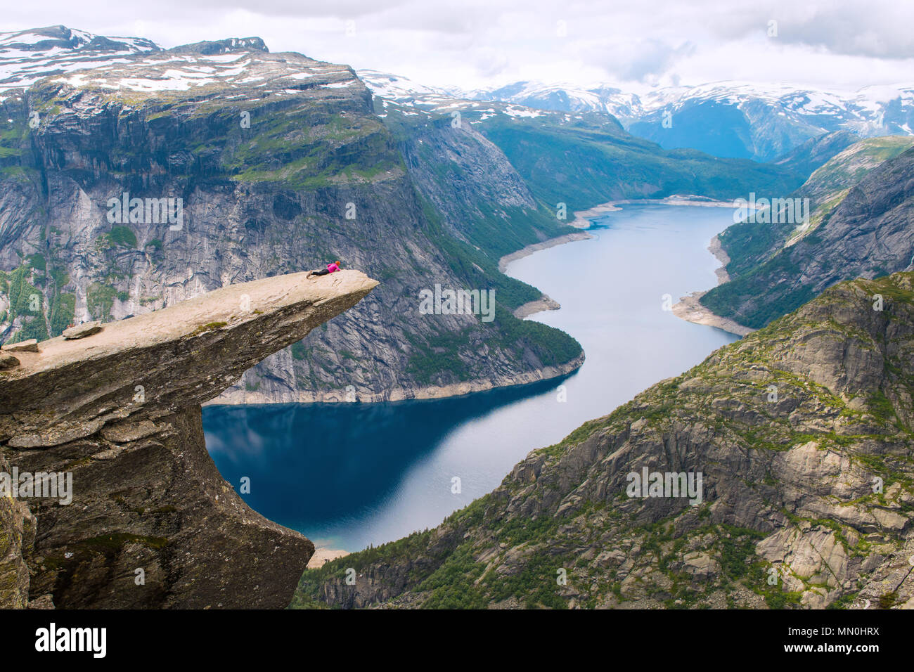 Sportliche Frau posiert auf Trolltunga. Glückliche Wanderer genießen die schönen See und gutes Wetter in Norwegen. Stockfoto