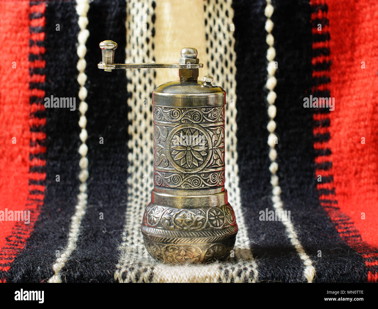 Türkische vintage Hand spice Grinder, alternativ "Türkisch Pfeffer Mühle, auf einem alten handgewebte Gewebe. Stockfoto