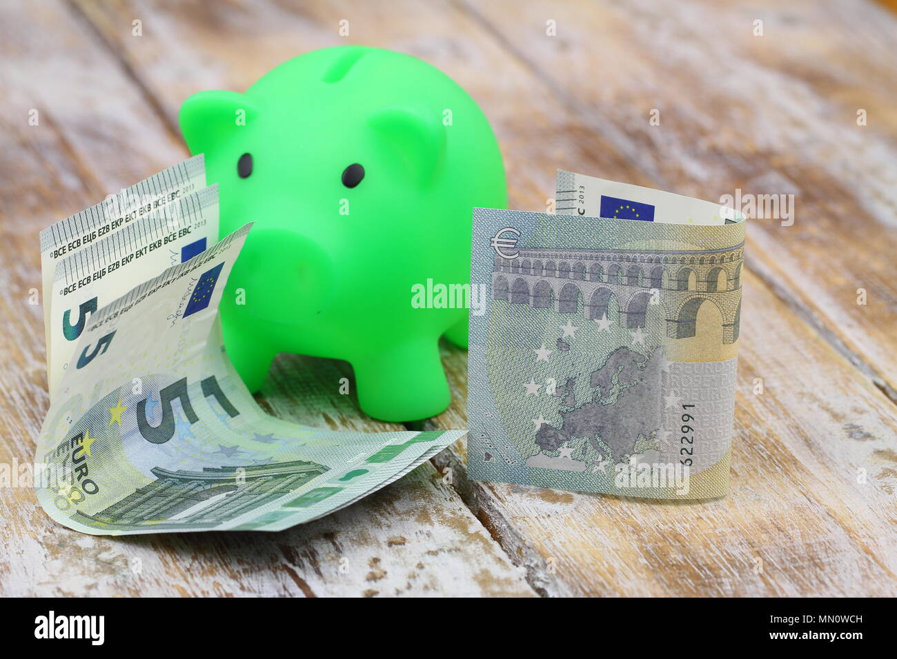 Zwei von fünf Euro nimmt mit Sparschwein auf Holzmöbeln im Landhausstil Oberfläche Stockfoto