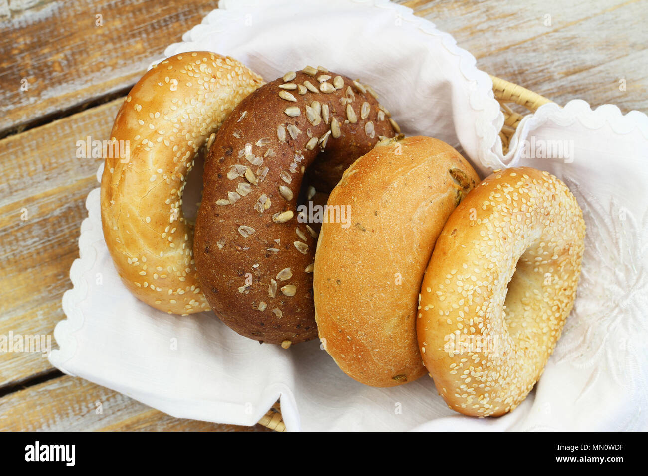 Auswahl an frisch gebackenen weißen, Sesam und braun Bagels im Brotkorb auf Holz- Oberfläche Stockfoto