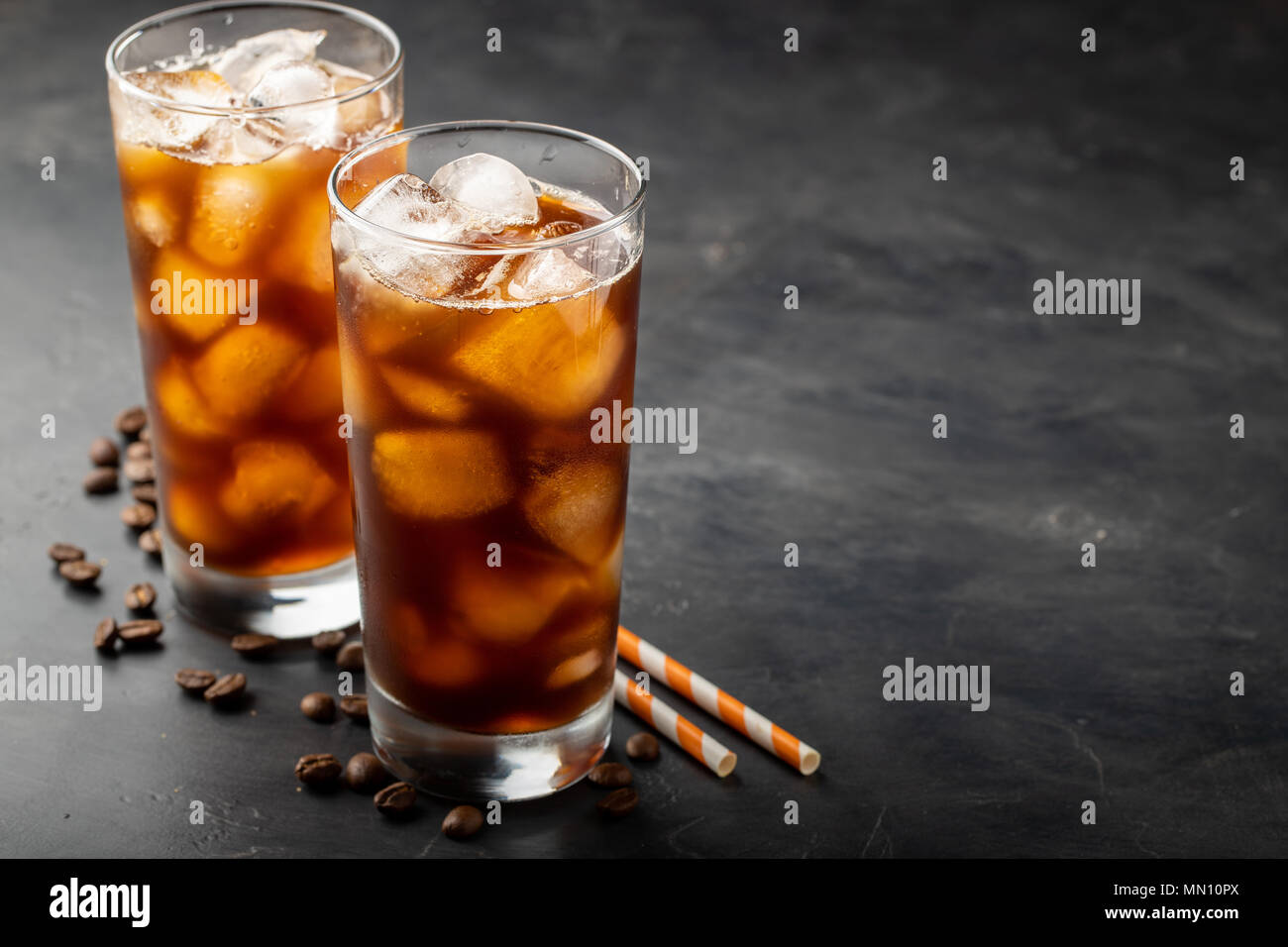 Eis Kaffee in einem großen Glas über und Kaffeebohnen auf einem alten rustikalen Holztisch. Kalten Sommer trinken auf einem dunklen Hintergrund mit Kopie Raum Stockfoto