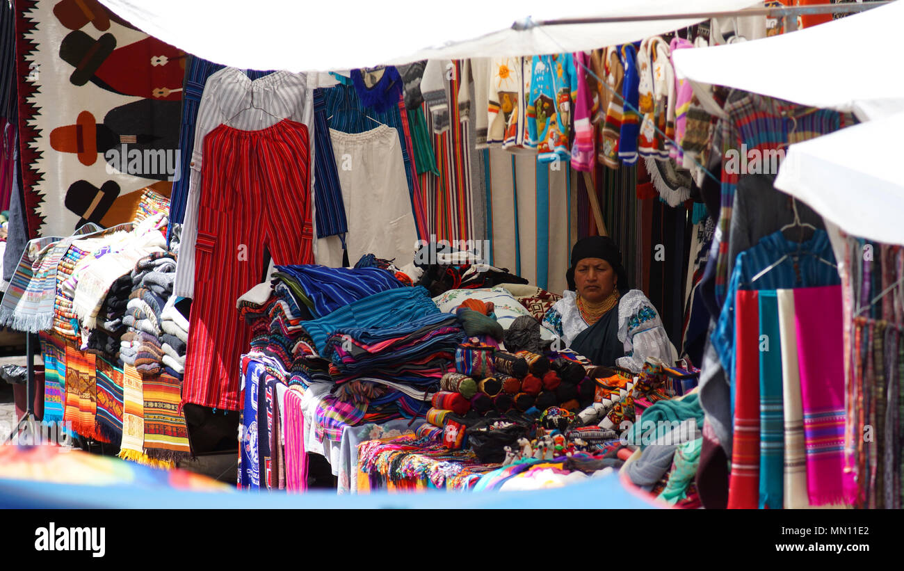 Indigene Frau sitzt und verkauft die Webereien und Kunsthandwerk in der Plaza de los Ponchos Stockfoto