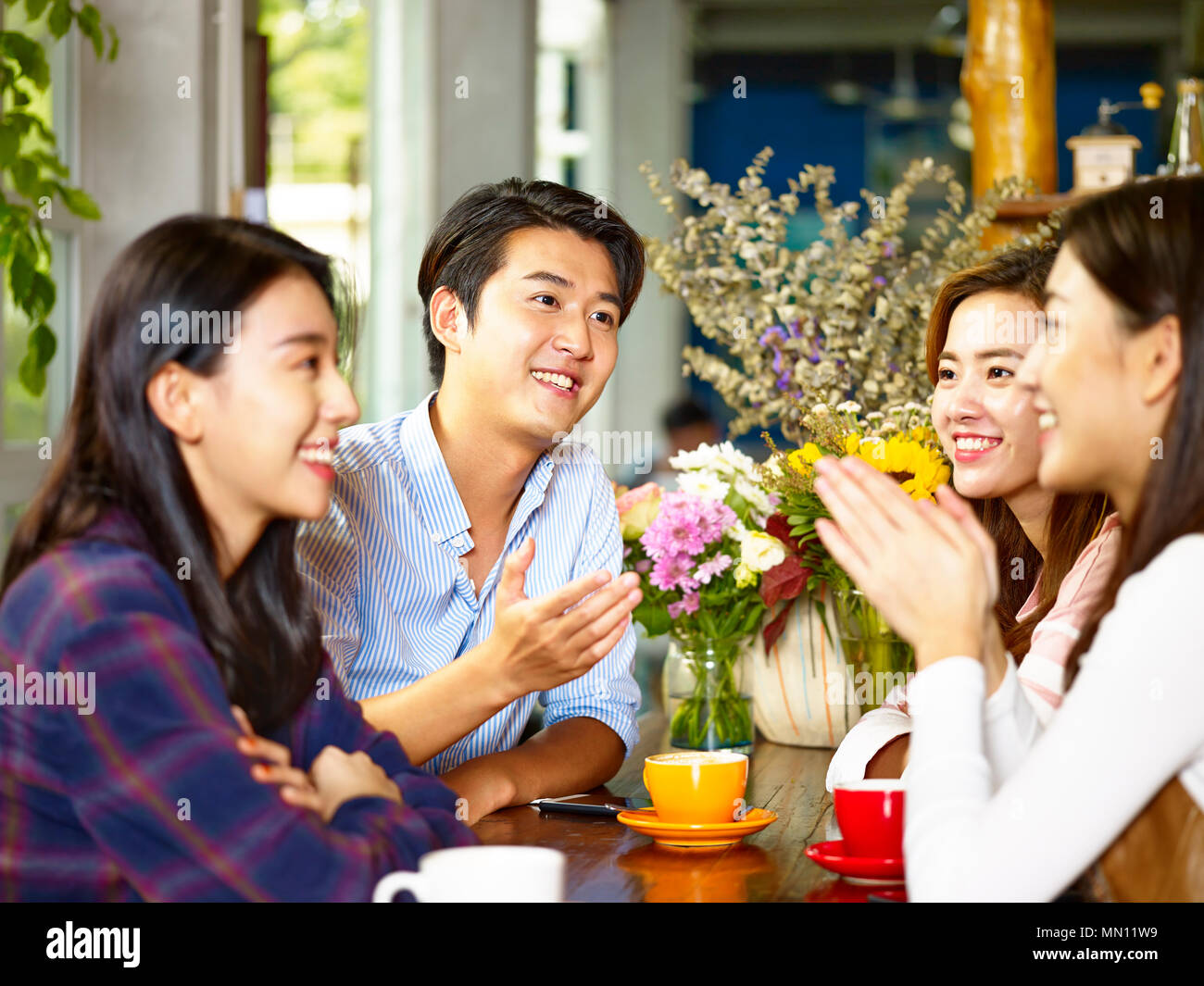 Vier Glückliche junge asiatische erwachsene Männer und Frauen im Chat Reden im Coffee Shop. Stockfoto