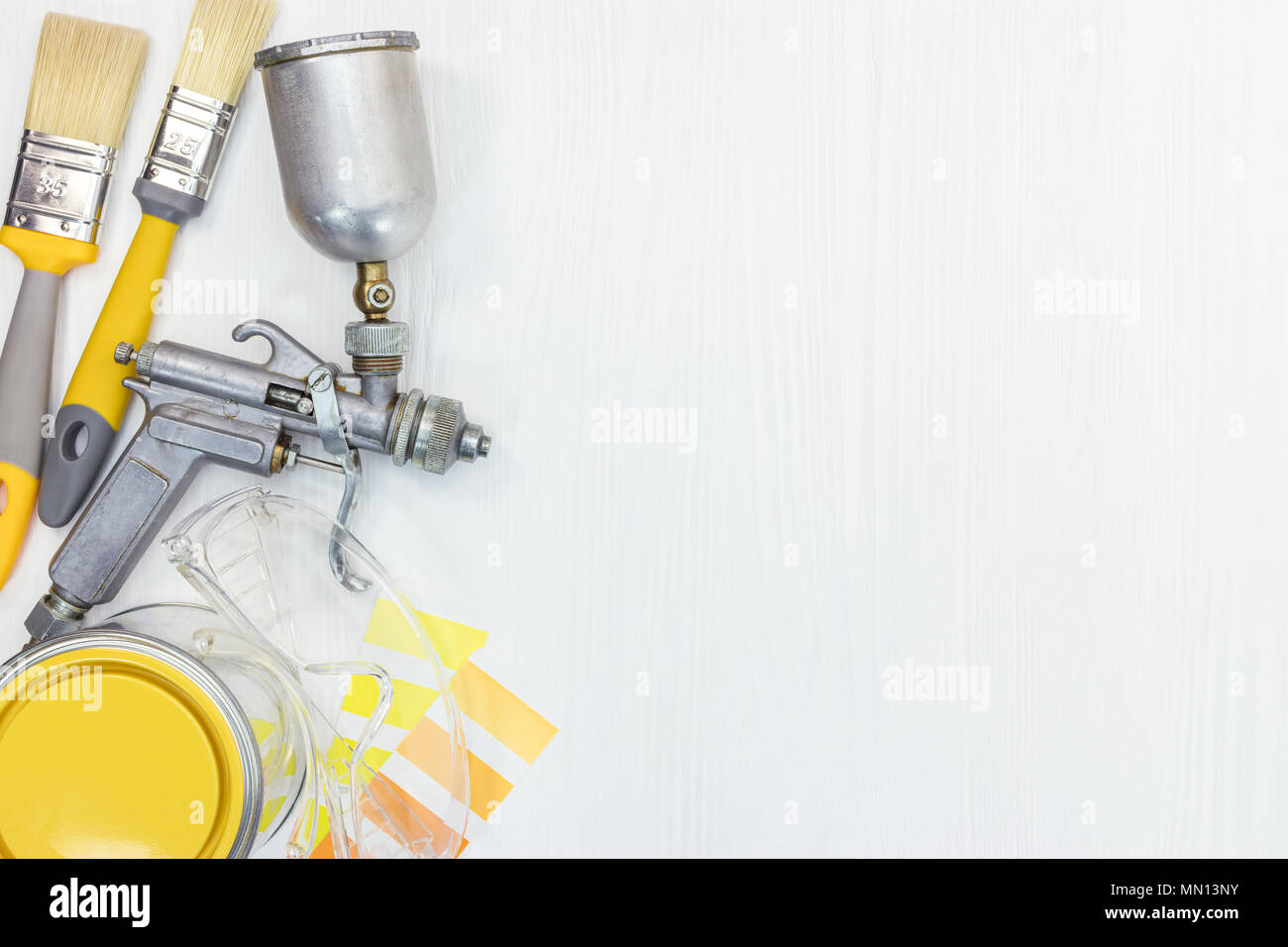 Hausarbeit tools flache Ansicht. Malerpinsel, können, Schutzbrille, Farbmuster und Spritzpistole auf weißem Holz- Hintergrund Stockfoto