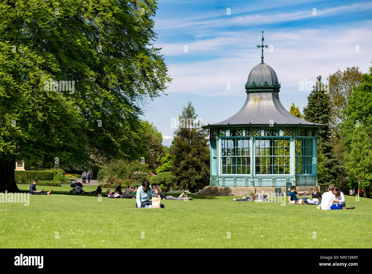 Die Menschen saßen in Weston Park, Sheffield, UK an einem sonnigen Tag, neben einem alten Musikpavillon. Stockfoto