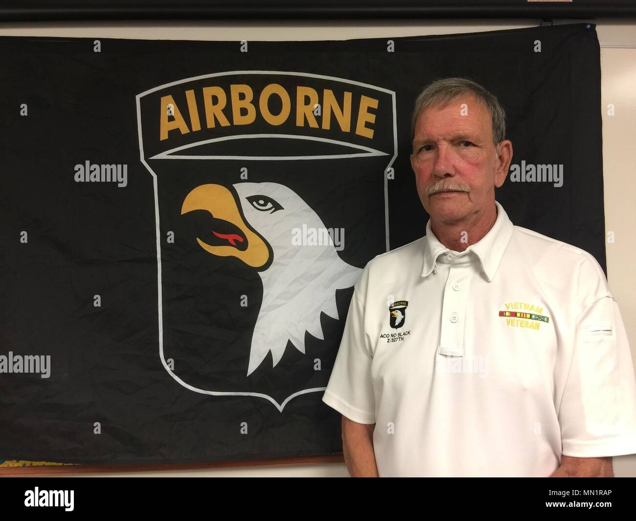 Dallas Braun, ein Vietnam Veteran, der Firma A, 2.BATAILLON, 327 Infanterie Regiment, 1. Brigade [eigene], Luftlandedivision stellt neben einem Screaming Eagle Flag, Aug 8, 2017 in Fort Campbell, Kentucky serviert. Braun, zusammen mit Tim Winterburg, Watson Baldwin, und Jay zu bewältigen, ist einer der Soldaten, die in den berühmten Vietnamkrieg Foto "Hilfe von Oben" von Kunst Greenspon. Als das Foto gemacht wurde, Braun war auf dem Boden Grimassen in den Schmerz von einer Verletzung während eines Feuergefechts mit der NVA getragen. (U.S Armee Foto von Sgt. William White) Stockfoto