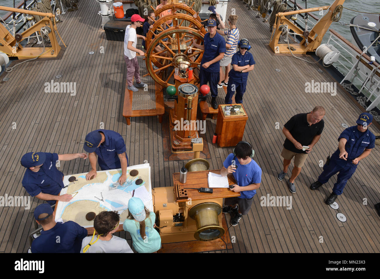 USCGC Eagle (WIX-327) ist eine 295 Fuß lange, dreimastige Barke, die 1936 in Deutschland gebaut wurde und 1946 als Trainingsschneider bei der United States Coast Guard in Betrieb genommen wurde. Das Archivbild dokumentiert Besatzungsmitglieder, die es einschifften Gästen, darunter Kinder der Gold Star Familie und Marinekadetten, erlauben, das Schiff zu steuern, während sie am 14. August 2017 im Atlantik unterwegs nach Baltimore sind. Stockfoto