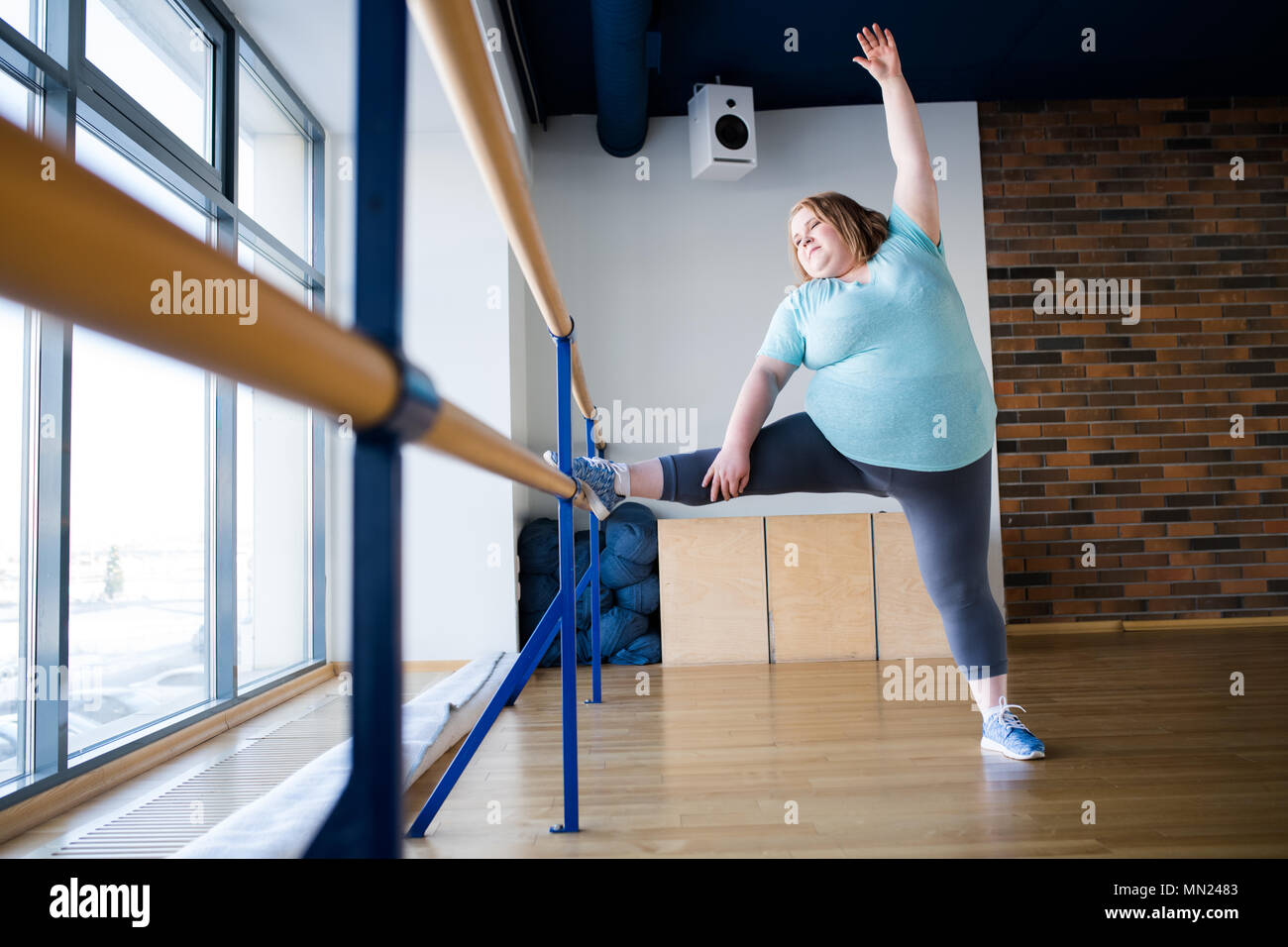 In voller Länge Porträt der übergewichtigen Jungen Frau, Ballett stellt sich bei gymnastischen Bar im Tanz Klasse, kopieren Raum Stockfoto