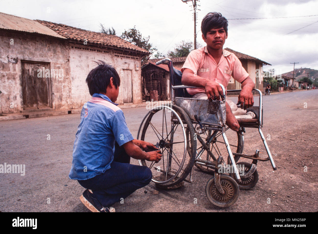 Managua, Nicaragua, Juli 1981; eine Sandinistische Kriegsveteran und doppeltes amputee hat seinen Rollstuhl angepasst. Stockfoto