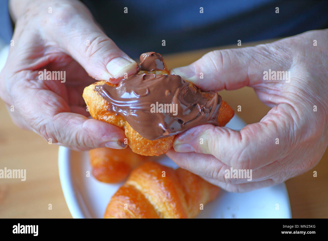 Ein Mann hält einen Mini-Croissant mit Nutella abgedeckt Stockfoto