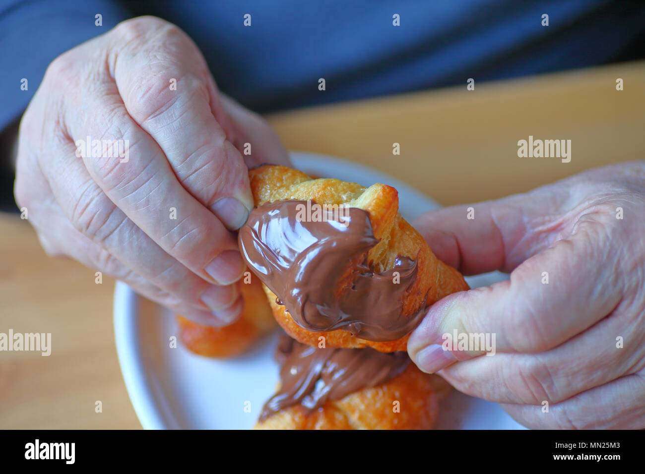 Ein Mann hält einen Mini-Croissant mit Nutella abgedeckt Stockfoto