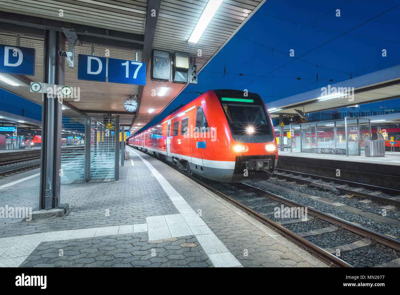Hochgeschwindigkeitszug auf dem Bahnhof in der Nacht in Nürnberg, Deutschland. Moderne Intercity Zug auf dem Bahnsteig mit illumintain. Pendler rot Stockfoto