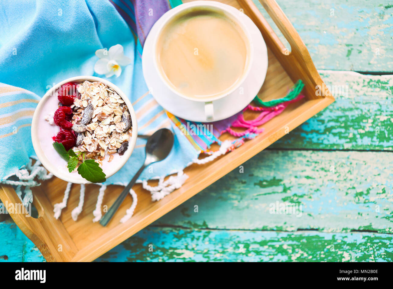 Tasse Müsli mit Joghurt und Obst auf Türkisfarbenem Hintergrund Stockfoto