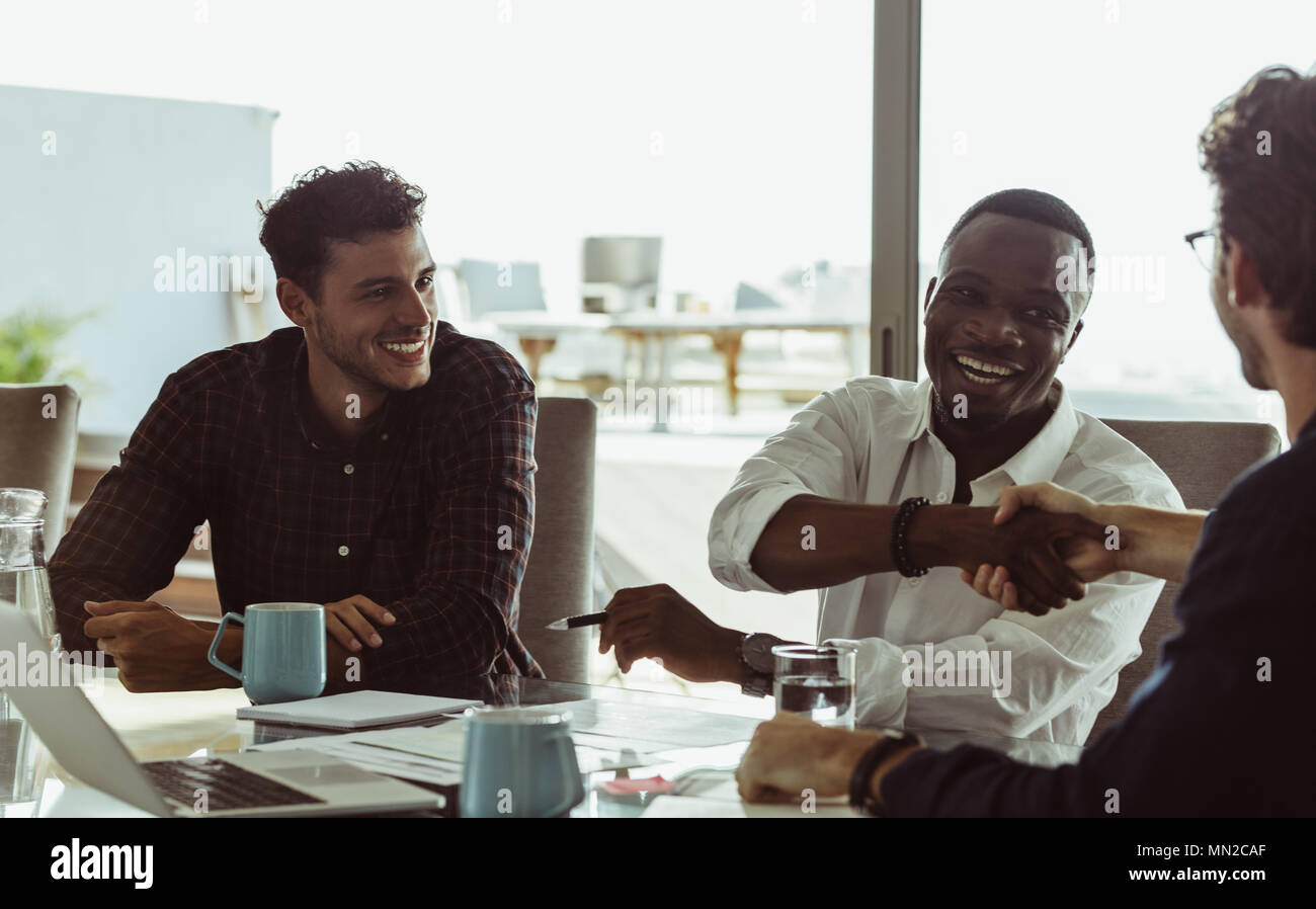 Unternehmer diskutieren Arbeit am Konferenztisch Sitzen im Büro. Männer die Hände schütteln und lächelnd während einer Konferenz. Stockfoto