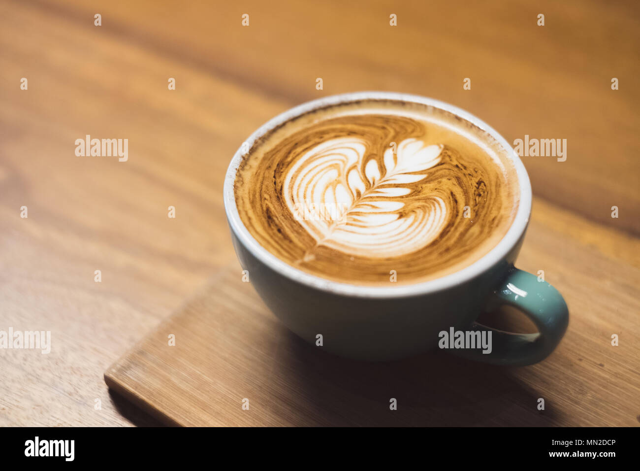 Close up heißen Cappuccino Tasse mit Herzform latte Kunst auf Holz Tisch im Cafe, Drak Tone Filter, Essen und Trinken Stockfoto