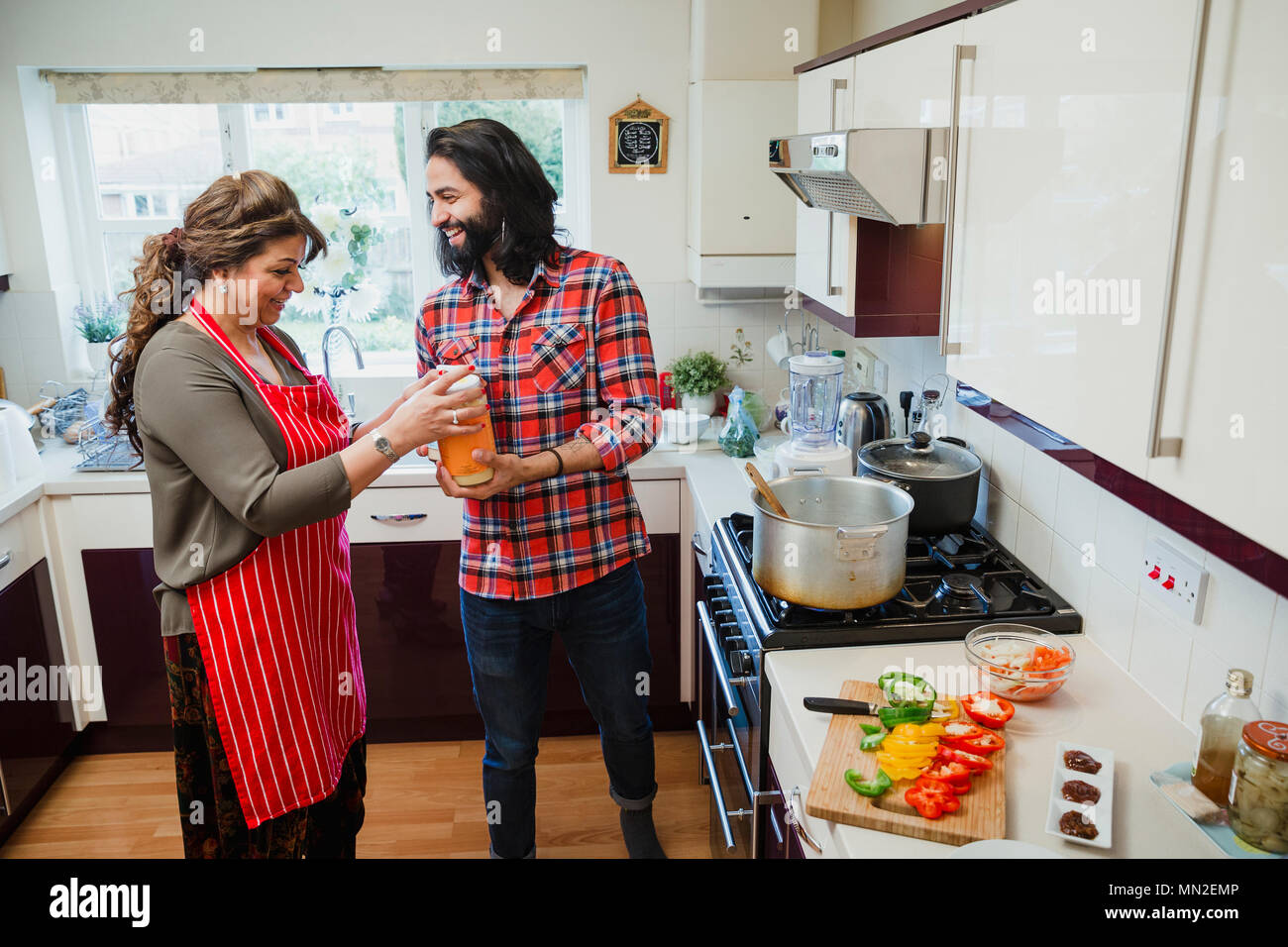 Mitte der erwachsene Mann hilft seiner Mutter, dass sie in der Küche ihres Hauses Curry. Sie öffnen eine Wanne gemahlener Ingwer. Stockfoto