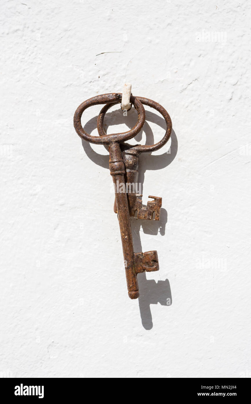 Zwei alte braune verrosteter Schlüssel hängen an einem Nagel gegen eine  weiße Wand Stockfotografie - Alamy