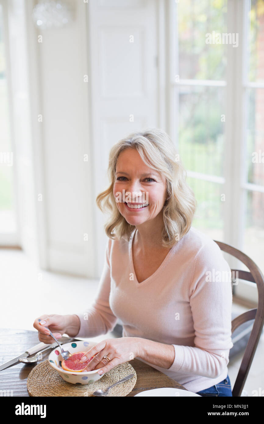 Porträt Lächeln reife Frau Grapefruit essen Stockfoto