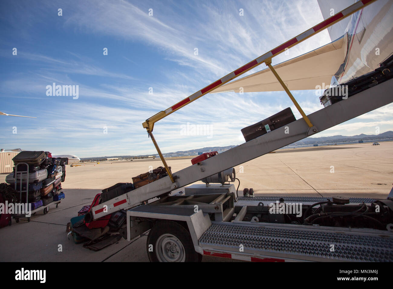 Das Gepäck wird in ein Passagierflugzeug auf dem Asphalt geladen. Schönen Tag am Flughafen mit dramatischen Wolken. Stockfoto