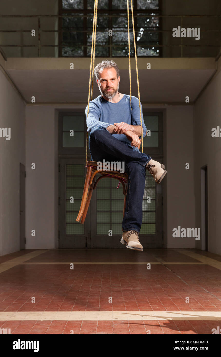 Guy hängenden sitzen auf dem Stuhl, alten industriellen Raum Hintergrund Stockfoto