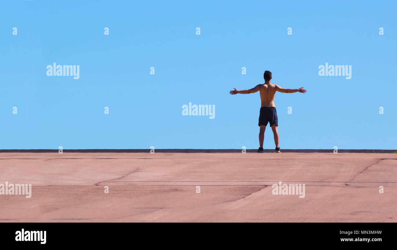 Junger Mann, Athlet mit offenen Armen vor blauem Himmel. Leere Raum für Editor's Text. Stockfoto