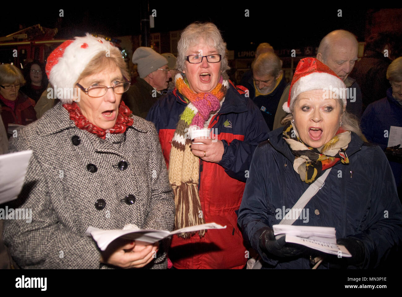 Die Menschen singen Weihnachtslieder im Freien in der lokalen Square, Liphook, Hampshire, UK. 15.12.2014. Stockfoto