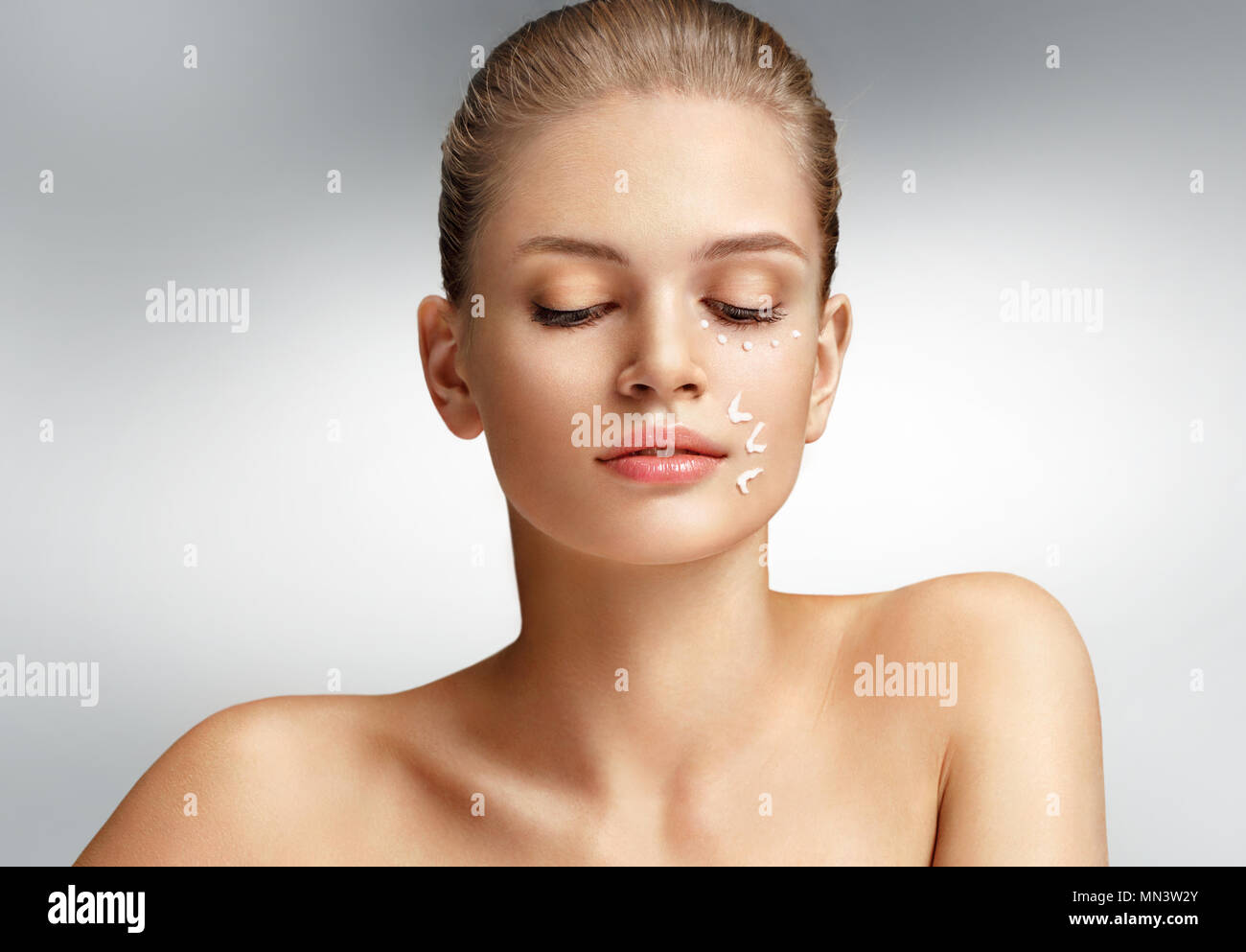Attraktive Frau mit perfekter Haut auf grauem Hintergrund. Hautpflege Stockfoto