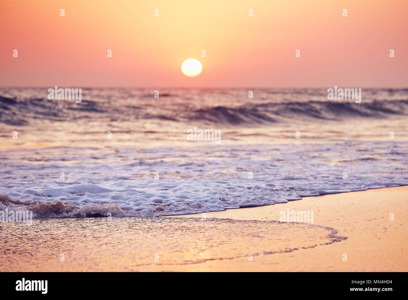 Idyllischen Sonnenuntergang auf der leeren tropischen Strand. Selektiver Fokus auf Schaum auf den Sand gegen Moody Himmel. Stockfoto