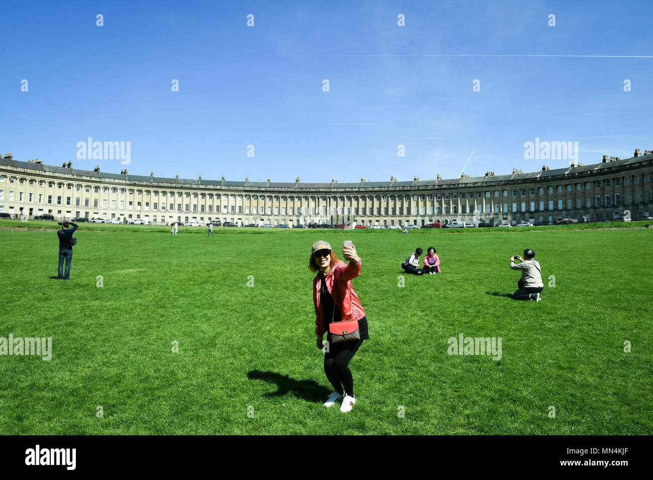 Ein Tourist nimmt eine selfie auf dem Rasen vor der Badewanne Royal Crescent, wo sonniges Wetter und Temperaturen im hohen Teens über Teile der South West bestehen. Stockfoto