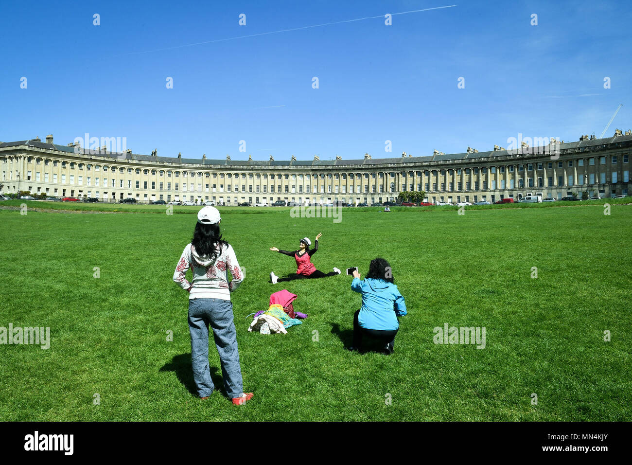 Touristen nehmen Sie Fotos von sich selbst auf dem Rasen vor der Badewanne Royal Crescent, wo sonniges Wetter und Temperaturen im hohen Teens über Teile der South West bestehen. Stockfoto