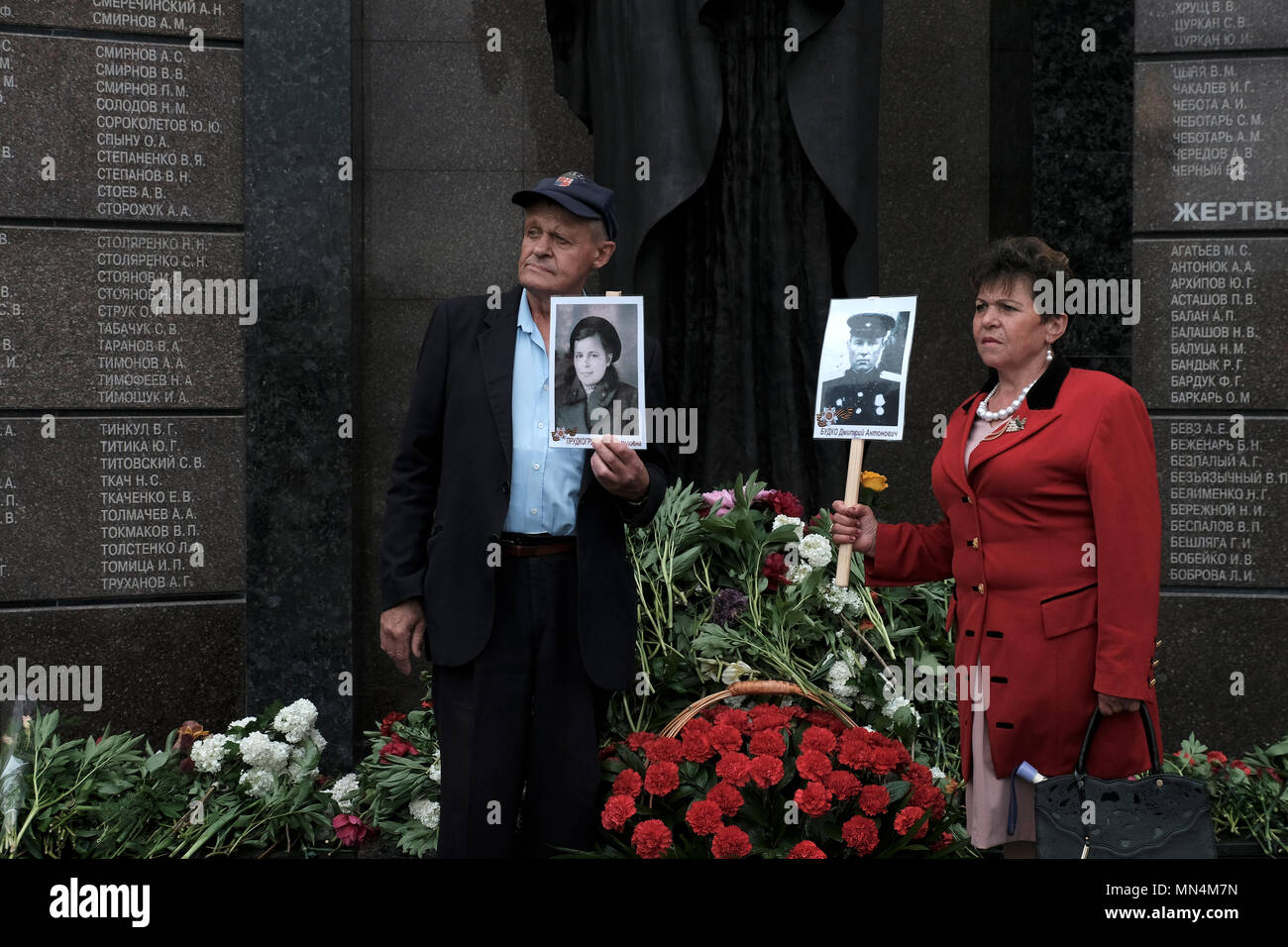 Menschen mit Fotos von Personen, die im Zweiten Weltkrieg Während der Tag des Sieges am 9. Mai, der den Sieg der Sowjetunion über Nazi-deutschland erinnert in der Gedenkstätte der Herrlichkeit, die die Veteranen und die Toten des Zweiten Weltkrieges gedenkt, die Soviet-Afghan Krieg gekämpft, und die 1990-1992 Transnistrien Krieg auf Suvorov Square in Tiraspol die Hauptstadt und das Verwaltungszentrum der international anerkannten Grenzen der Republik Moldau unter der De-facto-Kontrolle der nicht anerkannten Moldawischen Republik Transnistrien Pridnestrovian (PMR) seit 1992 genannt. Stockfoto