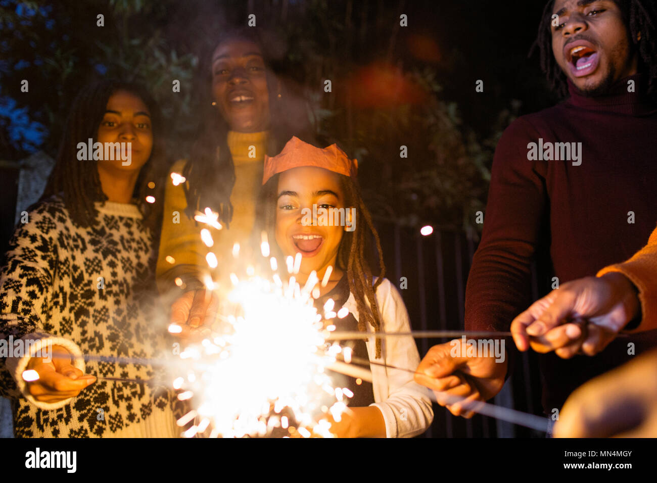 Verspielte Mädchen mit Wunderkerzen feiern mit Familie Stockfoto