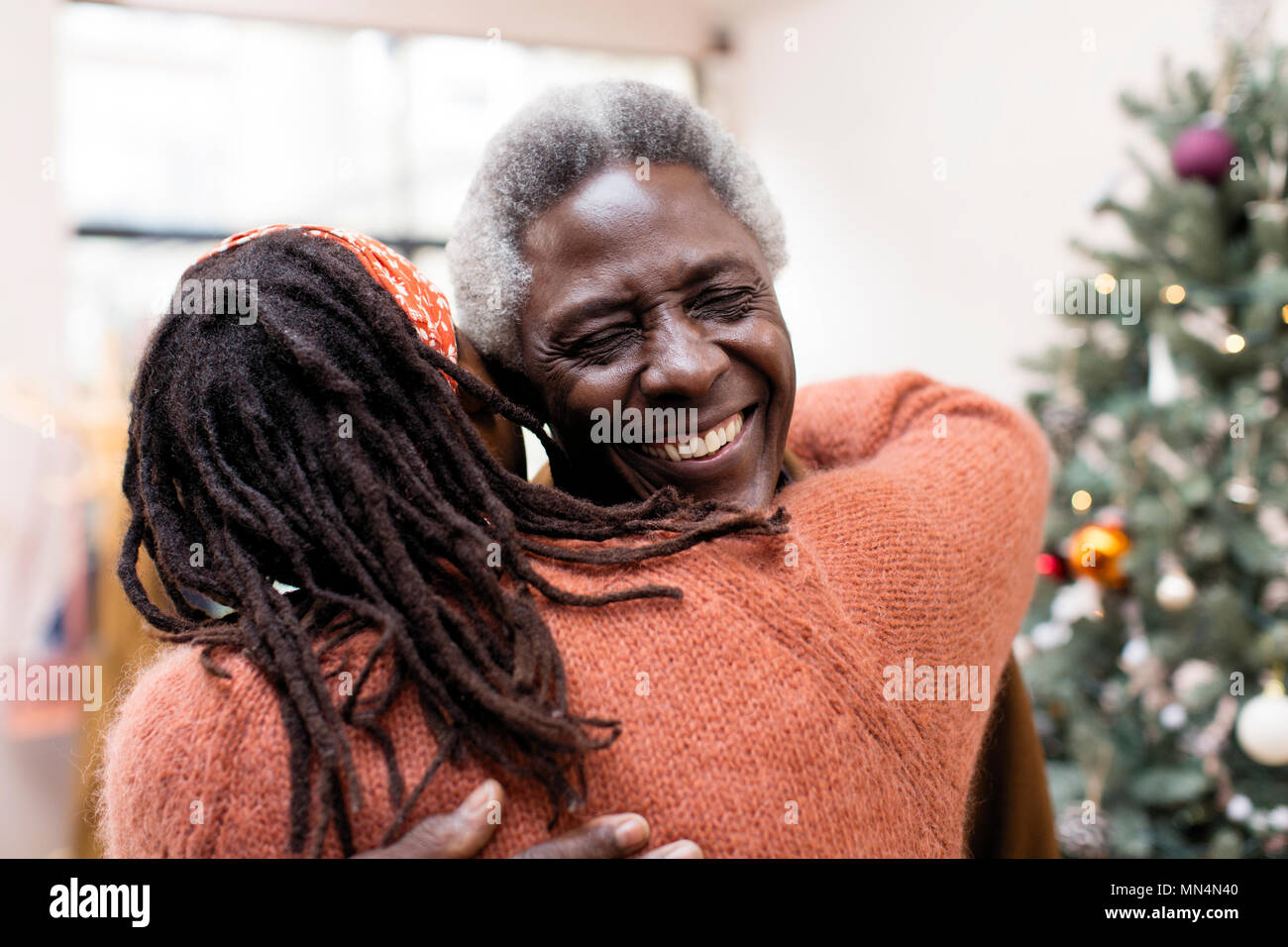 Gerne älteres Paar umarmen in der Nähe von Weihnachten Baum Stockfoto