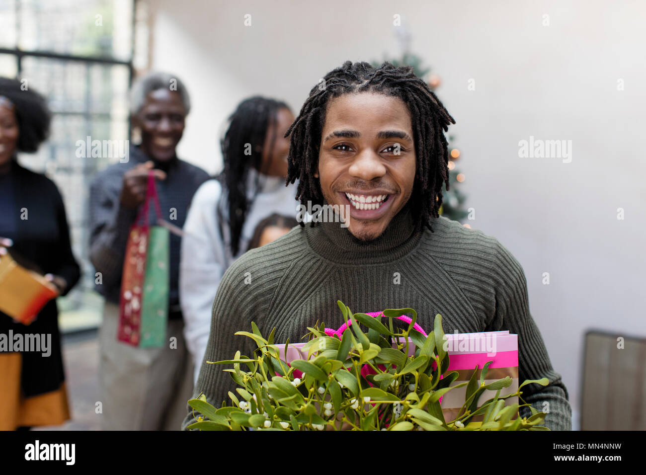 Porträt Lächeln, begeisterten jungen Mann mit Weihnachtsgeschenk und Mistel Stockfoto
