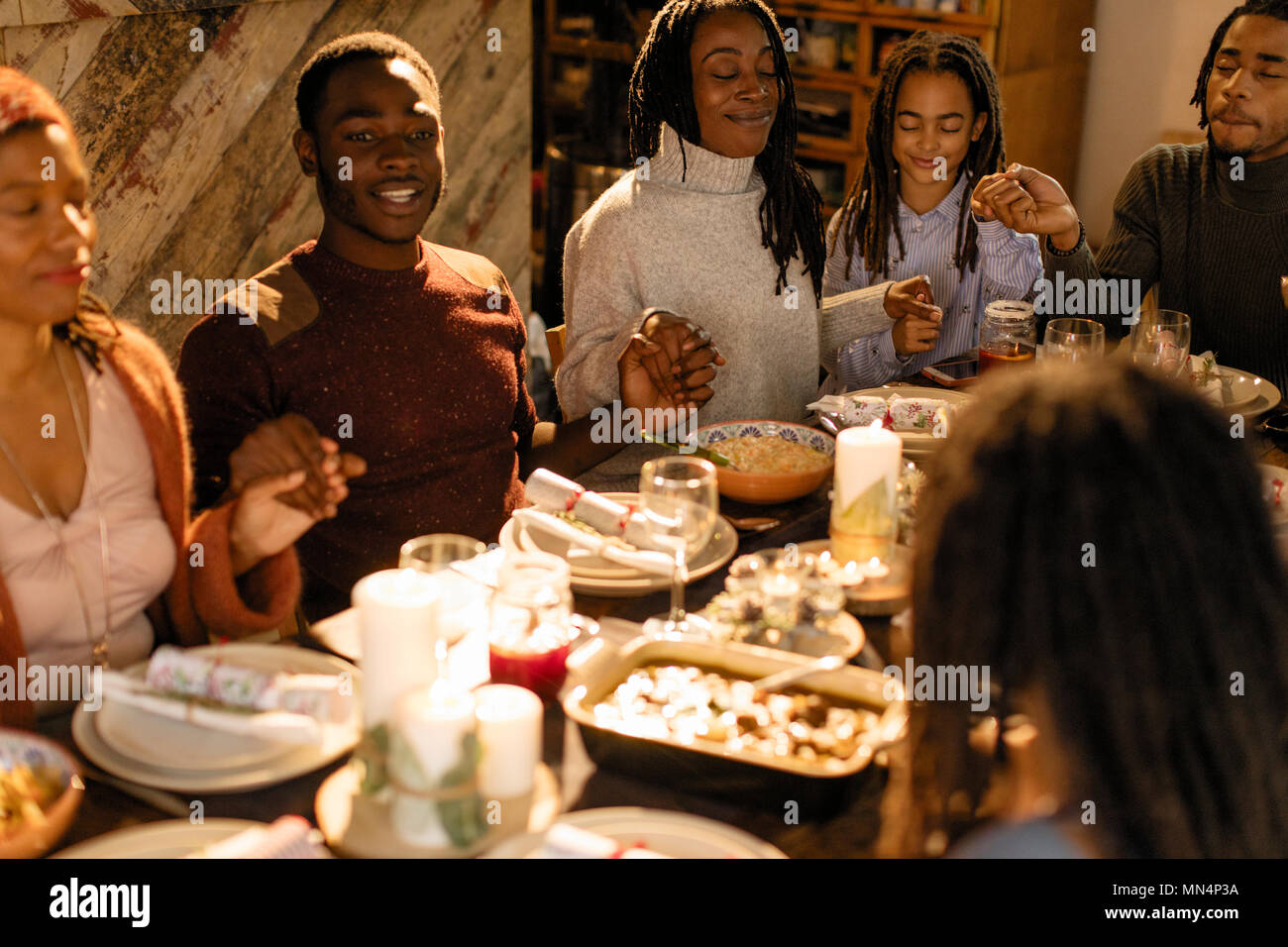 Familie halten sich an den Händen und beten an Weihnachten Abendessen Stockfoto
