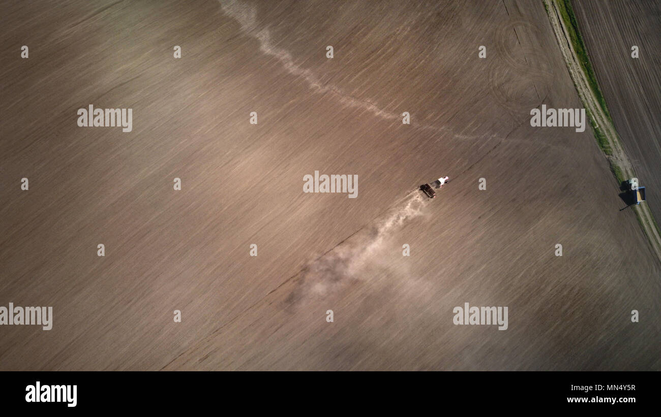 Luftaufnahme der Schlepper Pflüge die Feder Feld. Spring Season der landwirtschaftlichen Arbeiten auf Ackerland. Drone Foto Stockfoto
