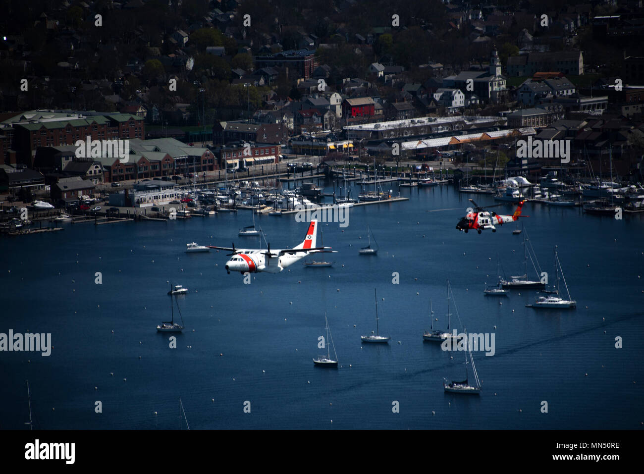 Am 8. Mai 2018 führten ein HC-144 Ocean Sentry von der Coast Guard Air Station Cape Cod und ein MH-60 Jayhawk Hubschrauber einen Überflug über Newport, Rhode Island, durch und überquerten die Coast Guard Cutter Eagle während der Eröffnung des Volvo Ocean Race Village. Das Archivbild dokumentiert die Formationsflucht während der Zeremonie. Stockfoto