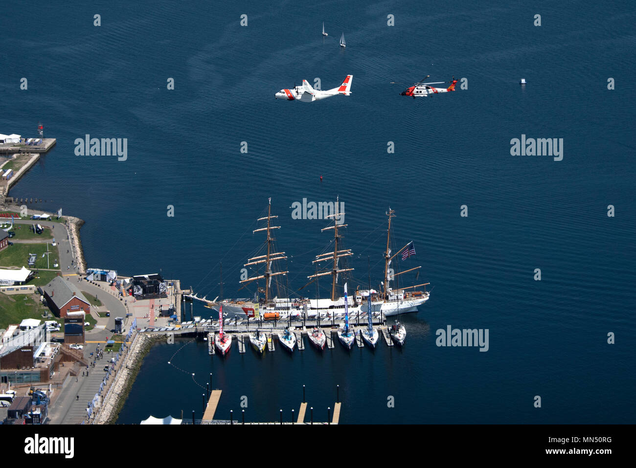 Am 8. Mai 2018 führten ein MH-60 Jayhawk und ein HC-144 Ocean Sentry von der Coast Guard Air Station Cape Cod einen Überflug über Newport, Rhode Island, durch und überquerten die Coast Guard Cutter Eagle während der Eröffnung des Volvo Ocean Race Village. Das Archivbild dokumentiert den koordinierten Flug über den Hafen. Stockfoto
