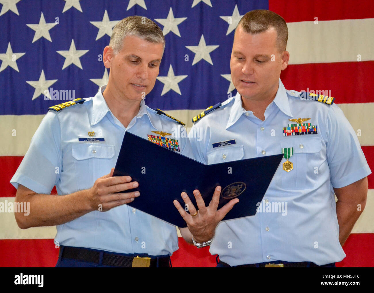 Lt.Cmdr. Jeff Jacobs, rechts, Crewmitglied bei Coast Guard Air Station Clearwater, Florida, und Kapitän Ward Sandlin, der Air Station Clearwater kommandierenden Offizier, lesen Sie die 2017 Kapitän John G. Witherspoon inspirierendem Leadership Award Jacobs Dienstag, 8. Mai 2018 auf der Station empfangen. Inspirierendem Leadership Awards werden von der Küstenwache der Führung gefördert und dienen die Küstenwache, die Männer und Frauen, die praktische Kenntnisse in der Führung und am besten veranschaulichen die Kernwerte der Küstenwache der Werte von Ehre, Respekt und Pflichterfüllung. (U.S. Coast Guard Foto) Stockfoto