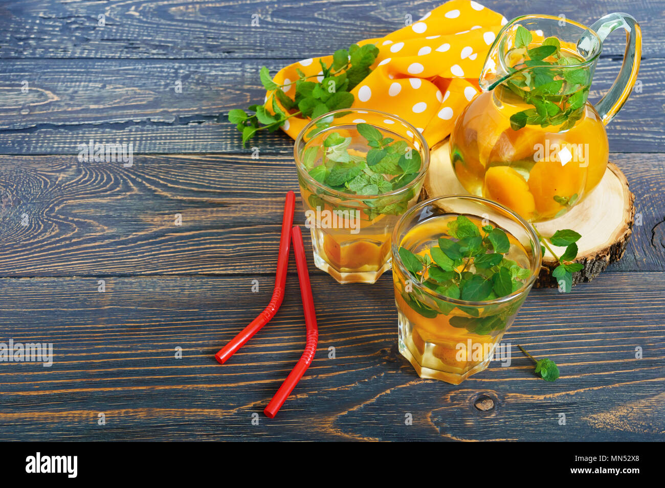 Sommer kalte Getränke. Kompott von Früchten. Köstlich erfrischendes Getränk mit Aprikosen und Minze im Glas auf einen hölzernen Tisch. Stockfoto