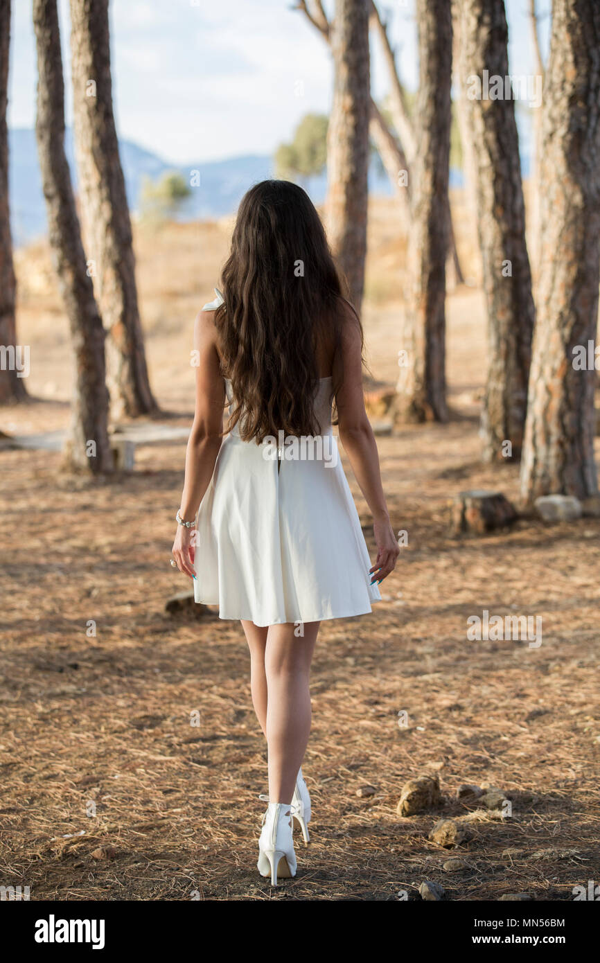 Ansicht der Rückseite eine Frau trägt ein weißes Kleid zu Fuß in den Wäldern Stockfoto