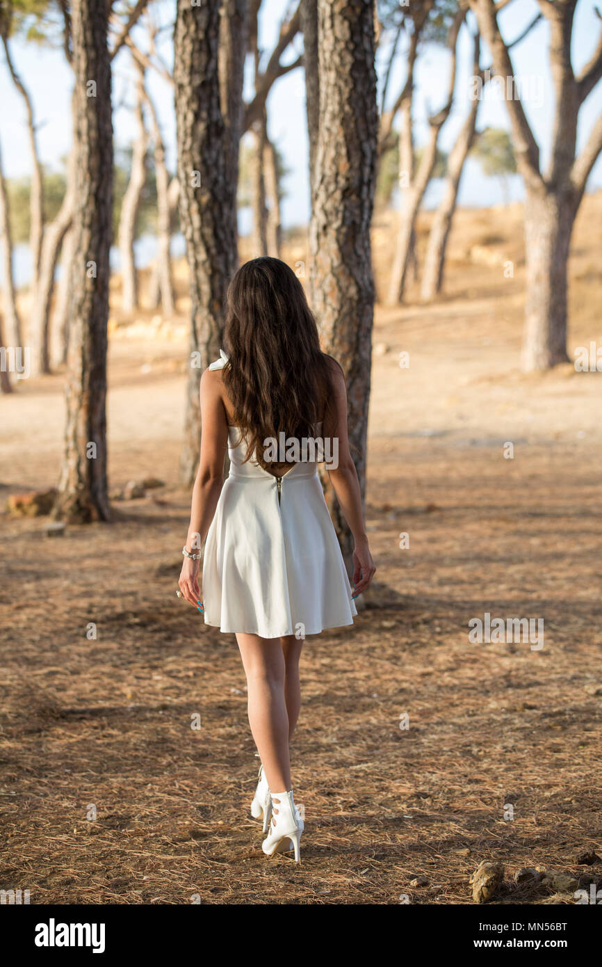 Ansicht der Rückseite eine Frau trägt ein weißes Kleid zu Fuß in den Wäldern Stockfoto