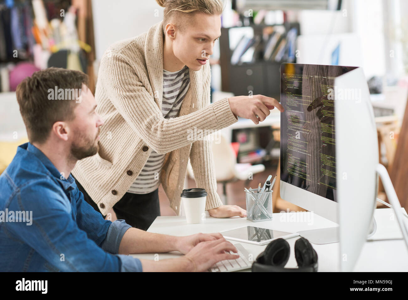 Porträt von zwei jungen kreativen Schreiben von Code an Schreibtisch und Computer, während sich die Zusammenarbeit mit Kollegen auf Startprojekt in modernen Büro Stockfoto