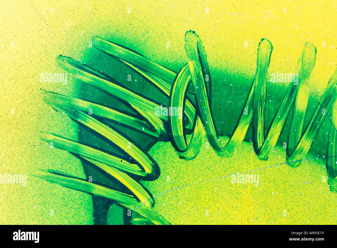 Spiralige Linien mit grünem Lack Kurven auf gelben Kunststoff Oberfläche. Abstrakte birght grunge Hintergrund Stockfoto