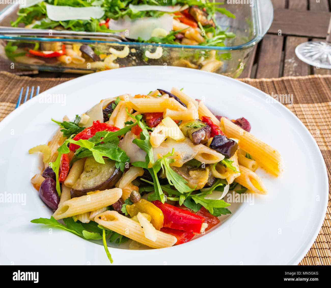 Tisch im Freien mit Pasta Salat serviert auf einem weissen Teller, crystal Weingläser und eine Flasche kühlen Weißwein Stockfoto