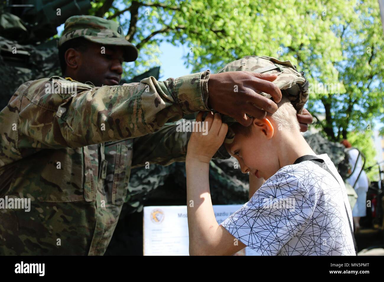 U.S. Army Staff Sgt. Jared Cherry seine Kevlar Helm auf einem polnischen Jungen, Gizycko, Polen, Mai, 2018. Bild mit freundlicher Genehmigung von SPC. Hubert Delany/Battle Group in Polen. () Stockfoto