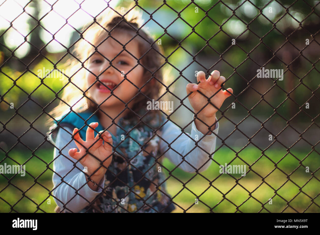Kleines Mädchen hinter einem Zaun. Stockfoto